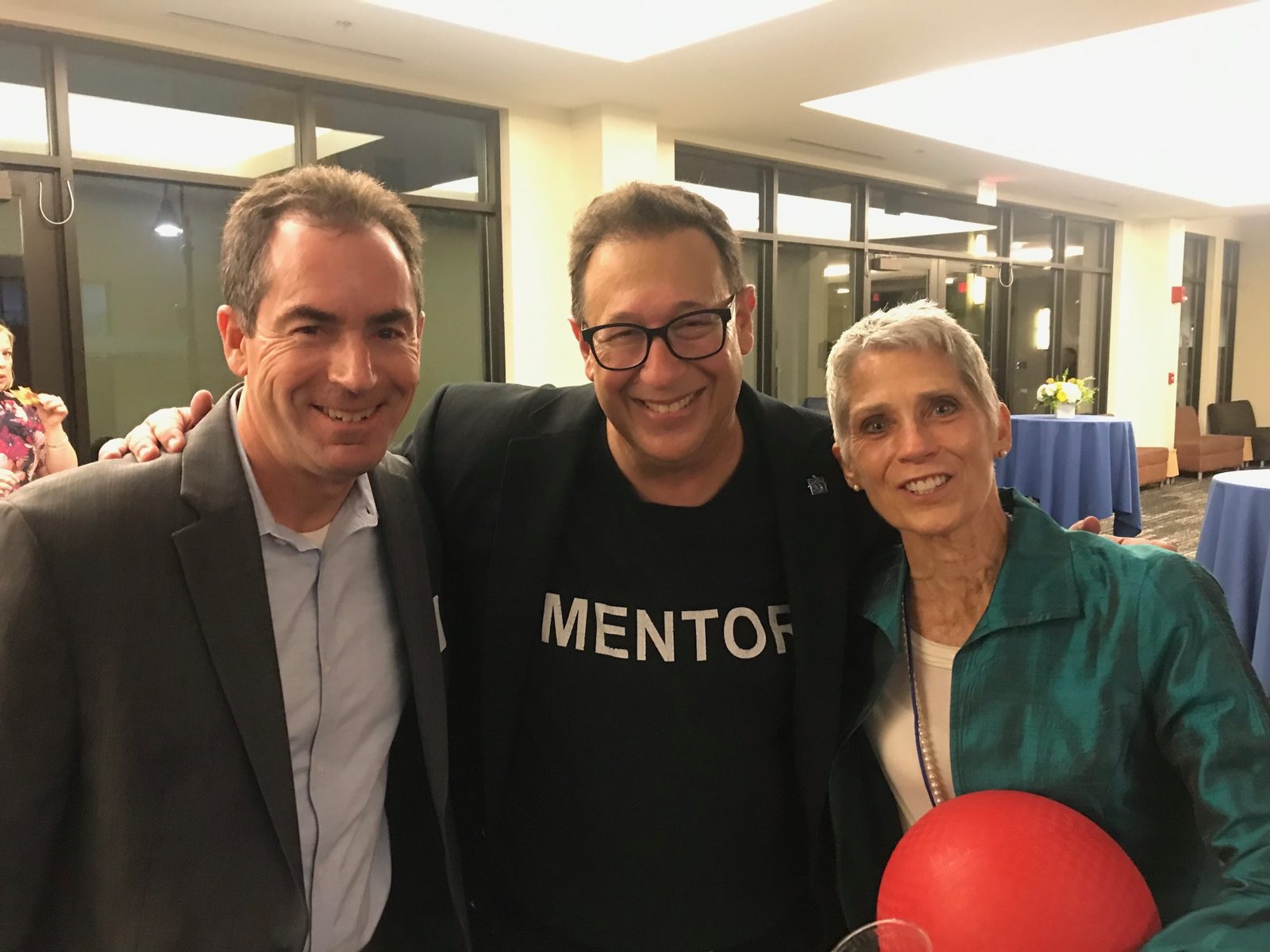 Scott Pansky in a Mentor shirt with two colleagues, one holding the red ball